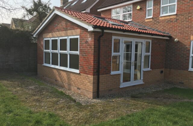 Single-storey Cambridge extension with a tiled gable roof, two-tone brickwork, white UPVC windows and french doors with full-height sidelights