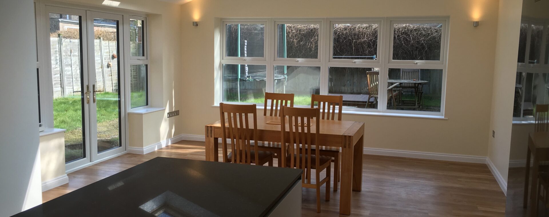 Single-storey extension in Cambridge with a dual-pitched vaulted ceiling, Velux roof windows, a central island and oak-effect flooring