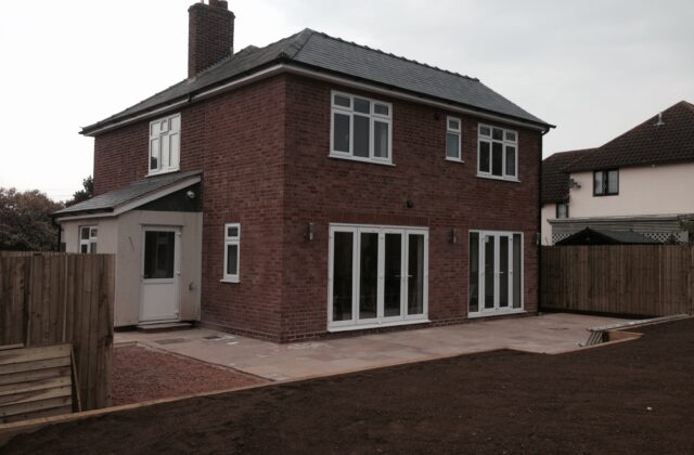 Double-storey extension in Caxton in new red brick masonry with a pitched slate roof, single-storey side porch and sandstone patio terrace