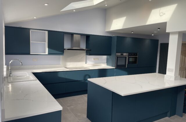 Dark teal kitchen with white quartz worktops and a central island in the Cherry Hinton extension, Cambridge