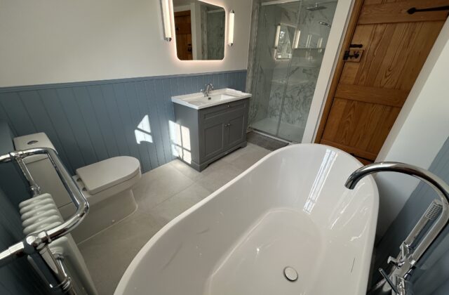 Newmarket bathroom with marble-effect shower enclosure, dark grey shaker vanity unit and back-lit LED mirror