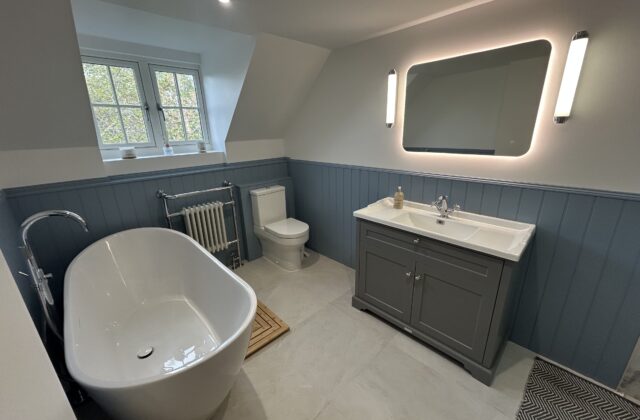 Spacious modern cottage-style bathroom in Newmarket with slate-blue panelling, freestanding bath and heated towel radiator