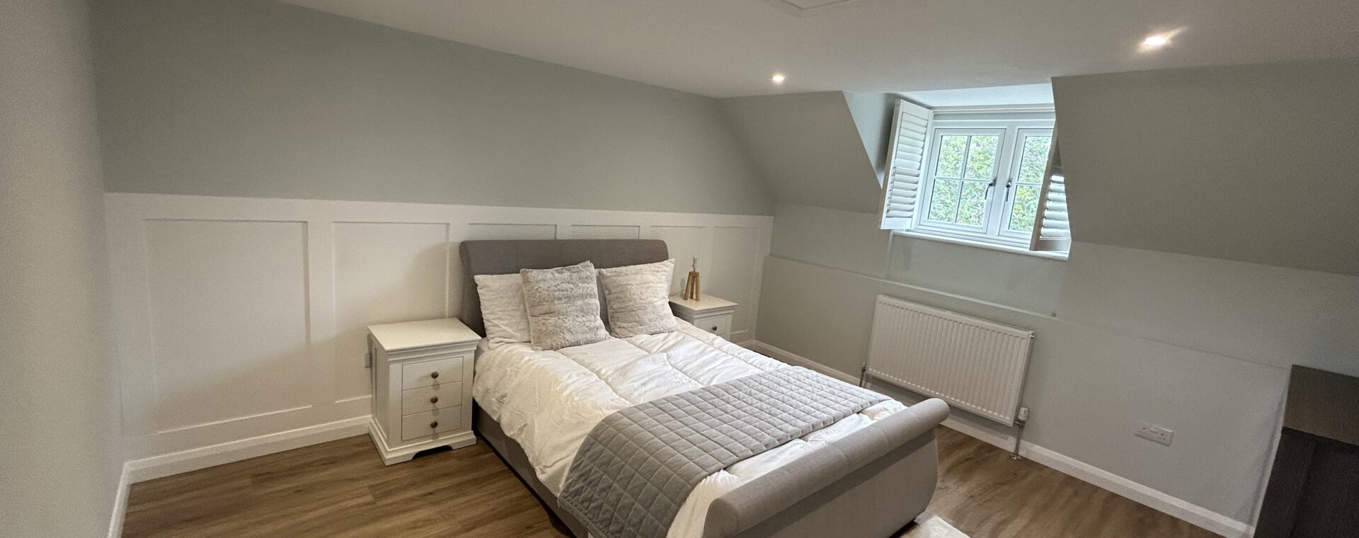 Refurbished eaves bedroom in Newmarket with white wall panelling, insulated drop-down loft hatch and LVT flooring