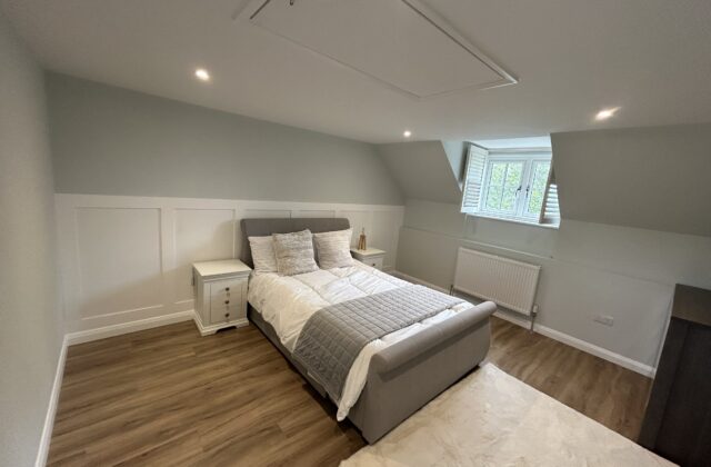 Refurbished eaves bedroom in Newmarket with white wall panelling, insulated drop-down loft hatch and LVT flooring
