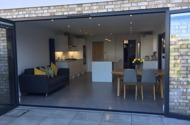 Open-plan kitchen and dining space in the Royston extension seen through full-width anthracite bifold doors