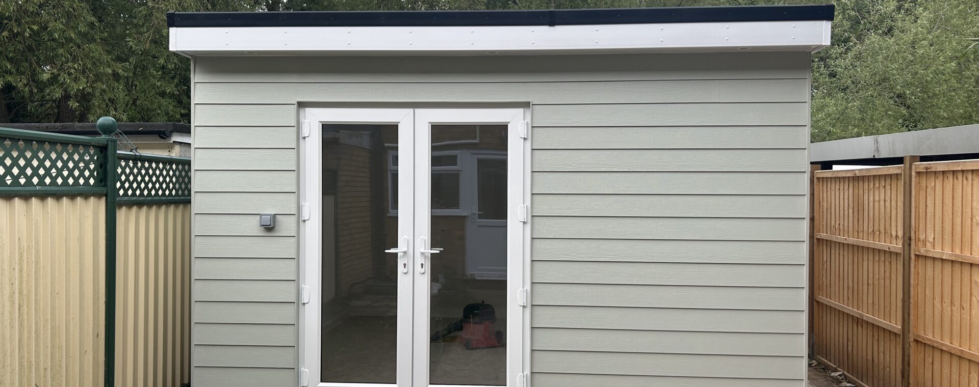 Bespoke garden room in Sawston with ivory hardie board cladding, white UPVC french doors, white fascias and an EPDM flat roof