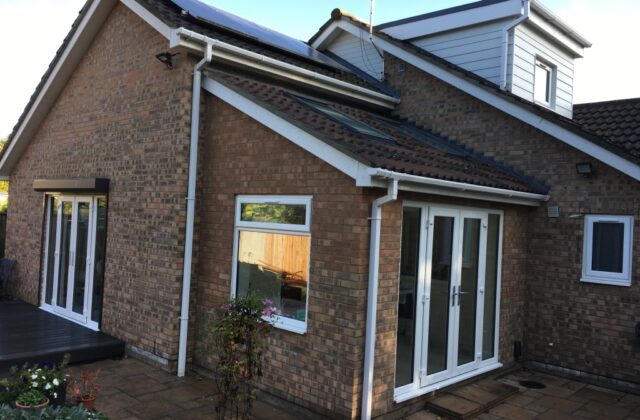 Brick house extension with a pitched tiled roof, dormer, french doors and composite decking