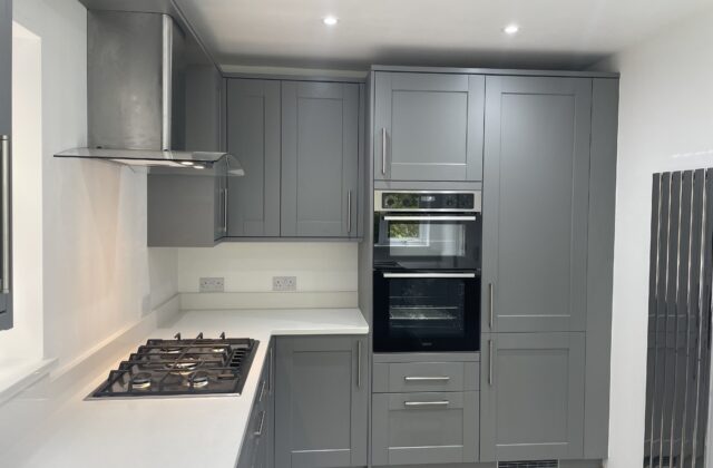 Slate-grey shaker kitchen refurbishment with integrated double oven, gas hob and white quartz worktops